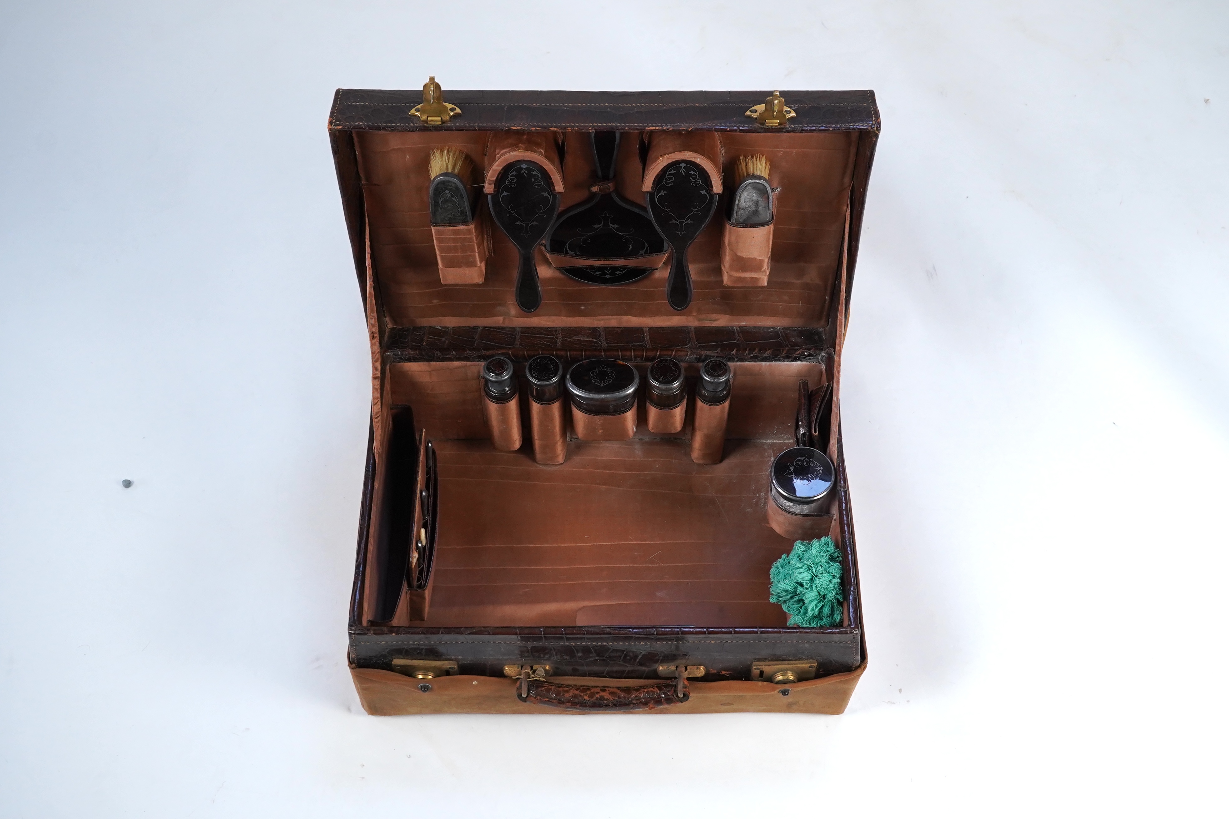 A George V crocodile skin travelling toilet case, containing twelve silver and tortoiseshell mounted accoutrements, by Collet & Anderson